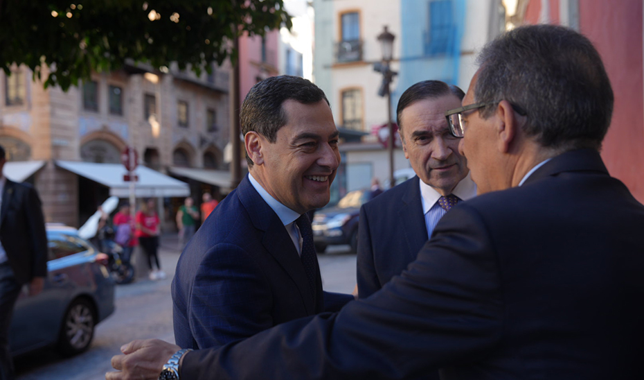 Juanma Moreno, junto al director de El Español, Pedro J. Ramírez, saluda a algunos de los asistentes al encuentro.